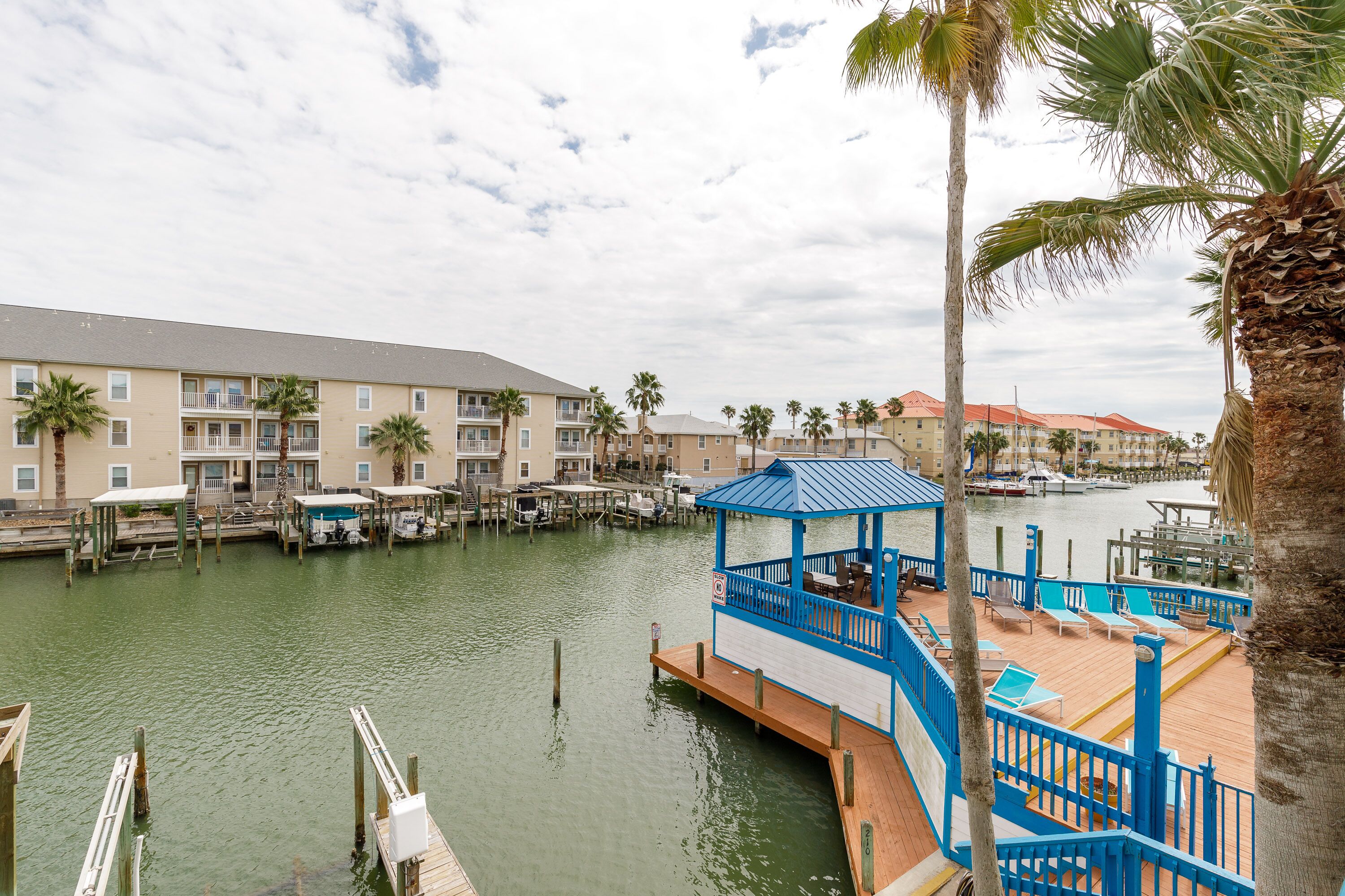 A waterfront hotel with multiple buildings, a dock, and a blue gazebo with seating.