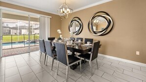 Uma sala de jantar com uma mesa posta para quatro pessoas, um candelabro e dois espelhos fixados na parede.