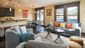 A modern living room with a grey sofa, a coffee table, and a dining area with a table and chairs.