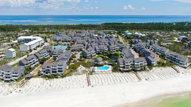 Un resort costero con varias edificaciones, una piscina y una playa.