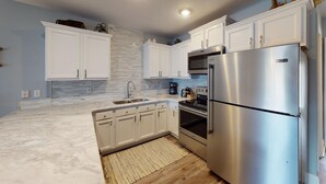Una cocina moderna con armarios blancos, un refrigerador de acero inoxidable y un horno integrado.