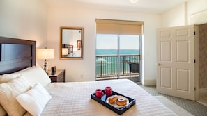 Relax in this serene hotel room with a large bed, ocean views, and a balcony.