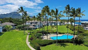 Un resort con piscina, palmeras y vista al océano.