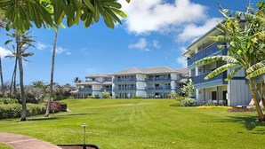 Un hotel con edificios de varios pisos, un césped cuidado y palmeras.