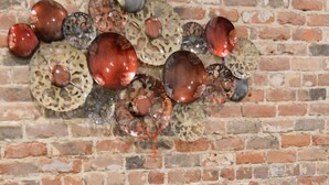 A brick wall with a decorative metal piece and a round table with stools.