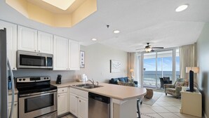 A modern kitchen with stainless steel appliances, a dishwasher, and a dining area with a view of the ocean. - Lighthouse 410 by Liquid Life (Gulf Shores)