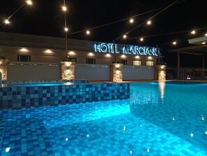 Relax by the pool surrounded by a checkered deck at Hotel Marciango.
