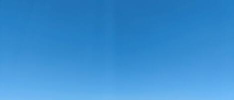 A clear blue sky with a crescent moon and distant mountains.