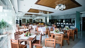 Un restaurante amplio con mesas y sillas de madera, manteles blancos y un diseño moderno en el techo.