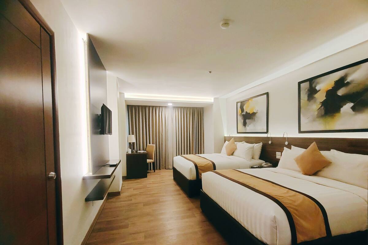 Una habitación de hotel con dos camas, un escritorio, una silla y un televisor.