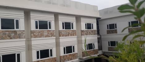 A multi-story building with a modern architectural design, featuring a series of balconies and a patterned facade.