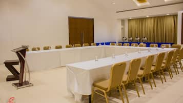 A conference room with a long table, chairs, a podium, and a curtain backdrop.