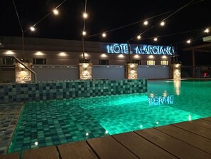 Relax by the pool at Hotel Marco, where a checkered tile pattern surrounds the water and a wooden deck awaits.