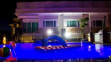A swimming pool with inflatable toys and a stone border.