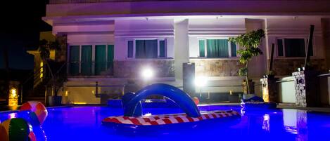 A swimming pool with inflatable toys and a stone border.