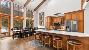 Una cocina amplia con armarios de madera, una isla grande con taburetes y vistas al exterior a través de ventanas grandes.