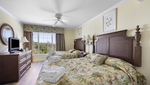 Una habitación de hotel con dos camas, televisión, cómoda y un ventanal con cortinas.