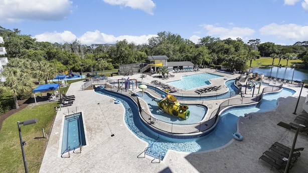 Un área de piscina con tobogán de agua, sillas de descanso y un pequeño edificio.