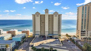Un hôtel de grande hauteur doté de nombreux balcons, d’un parking et offrant une vue sur la plage et l’océan.