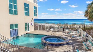 Un espace piscine doté d’un jacuzzi, de chaises longues et offrant une vue sur la plage.