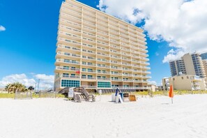 Ein Hochhotel mit zahlreichen Balkonen, direkt am Strand gelegen, mit blauem Himmel.