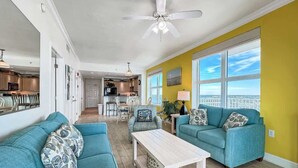 Un salon spacieux avec deux canapés de couleur turquoise, une table basse blanche et un mur d’accent jaune.