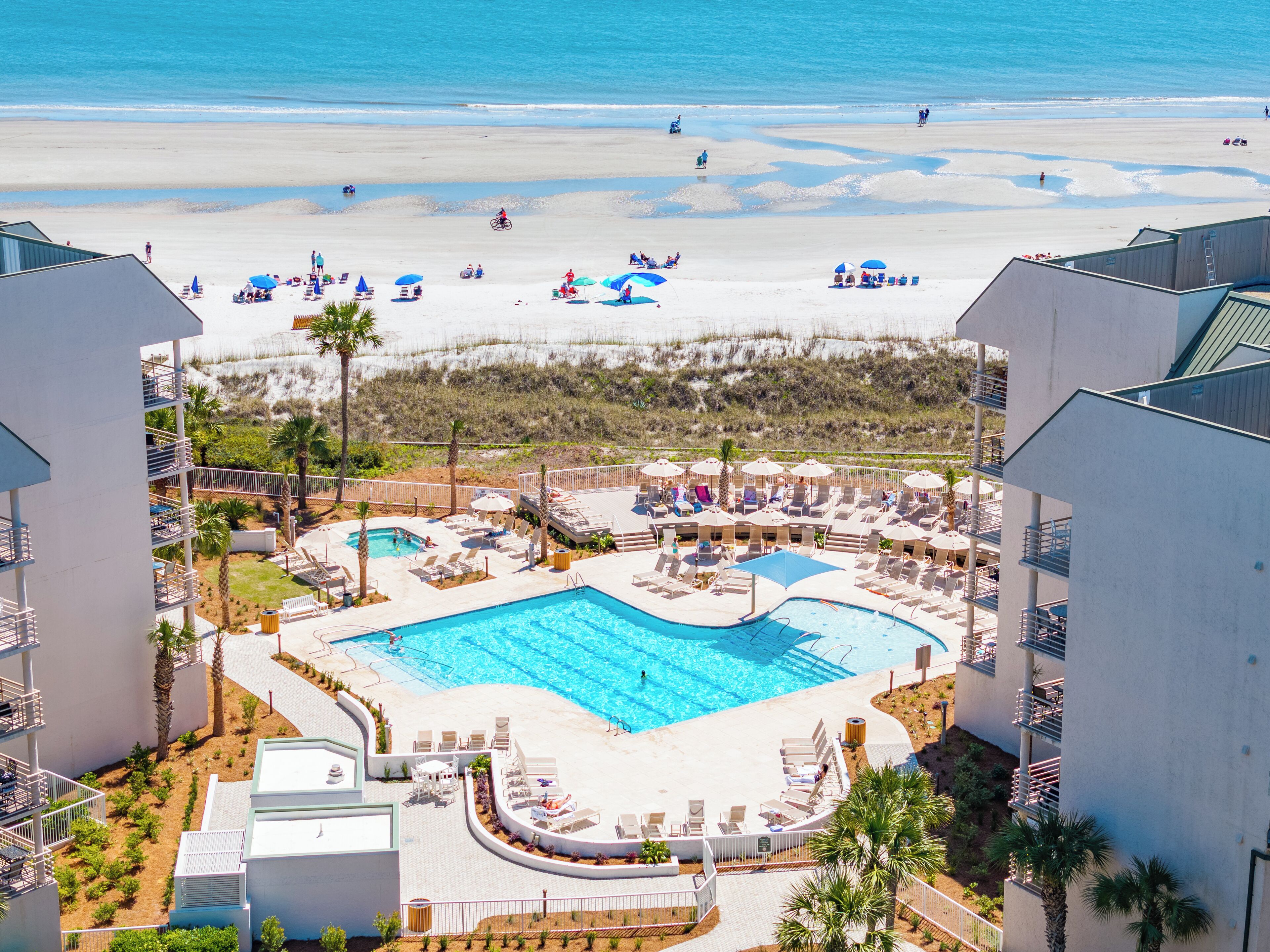 A resort with a swimming pool, beach, and multiple lounge areas.