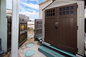 A wooden garage door with a window, a wooden fence, and a sandy path leading to a building.