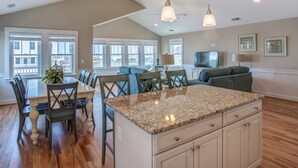 A spacious kitchen with a granite countertop, wooden cabinets, and a dining area with chairs and a table.