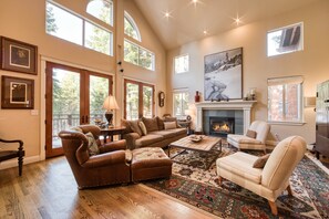 A spacious living room with a fireplace, leather sofas, a coffee table, and a large rug.