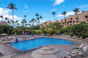 A swimming pool surrounded by palm trees and lounge chairs.
