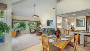 A spacious living area with a dining table set for four, a sofa, and a kitchen area with a refrigerator and sink. - Regency 220 Modern Spacious Full AC By Suite Paradise (Koloa)