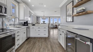 A modern kitchen with white cabinetry, stainless steel appliances, and a wooden floor.