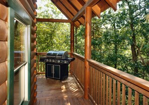 A wooden deck with a barbecue grill and a window. - Pigeon Forge | Pool Table | Hot Tub | WiFi | Resort Pool | Fireplace (PIGEON FORGE)