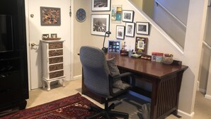 A home office with a desk, chair, and various framed pictures on the wall.