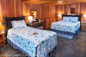 Una habitación con dos camas, paredes y techo de madera.