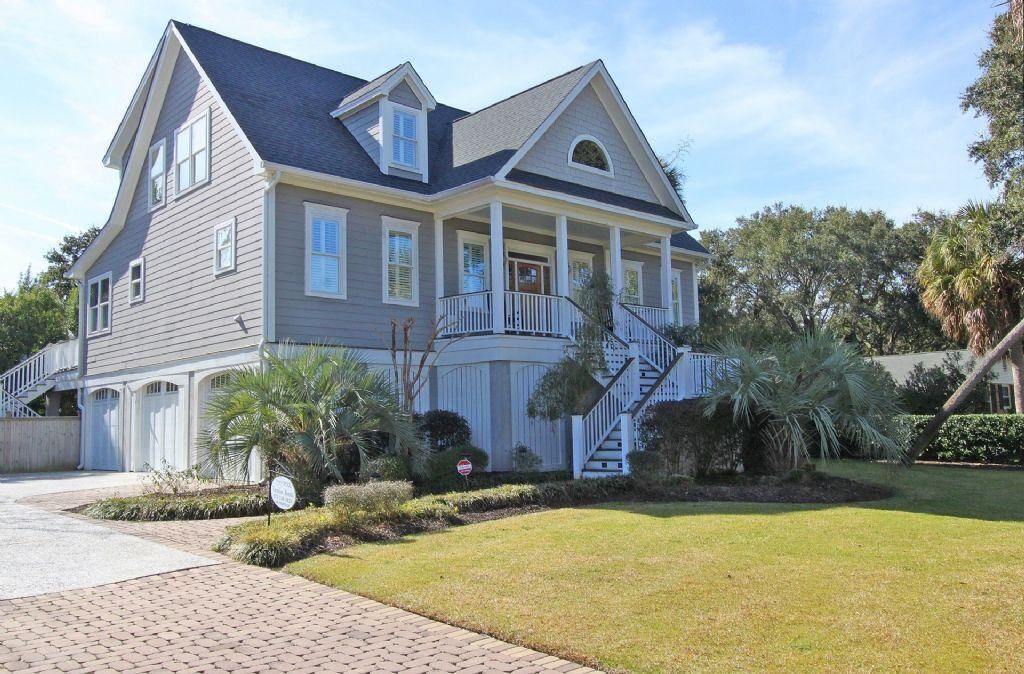 A two-story house with a wrap-around porch, a garage, and a well-maintained lawn.