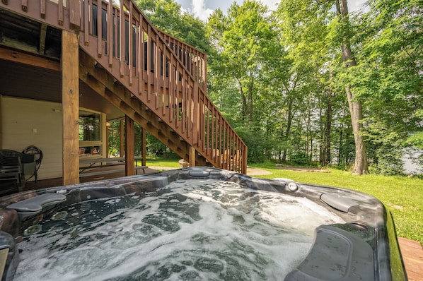 A hot tub with a wooden deck and stairs leading to a covered area.