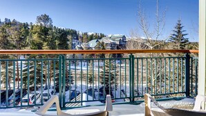 A deck with a green railing overlooking a snowy landscape with parked cars and buildings in the background. - Steps to Adventure, Remodeled Kitchen, Wi-Fi, Ski in/out, Gas Fireplace TE411 (Breckenridge)