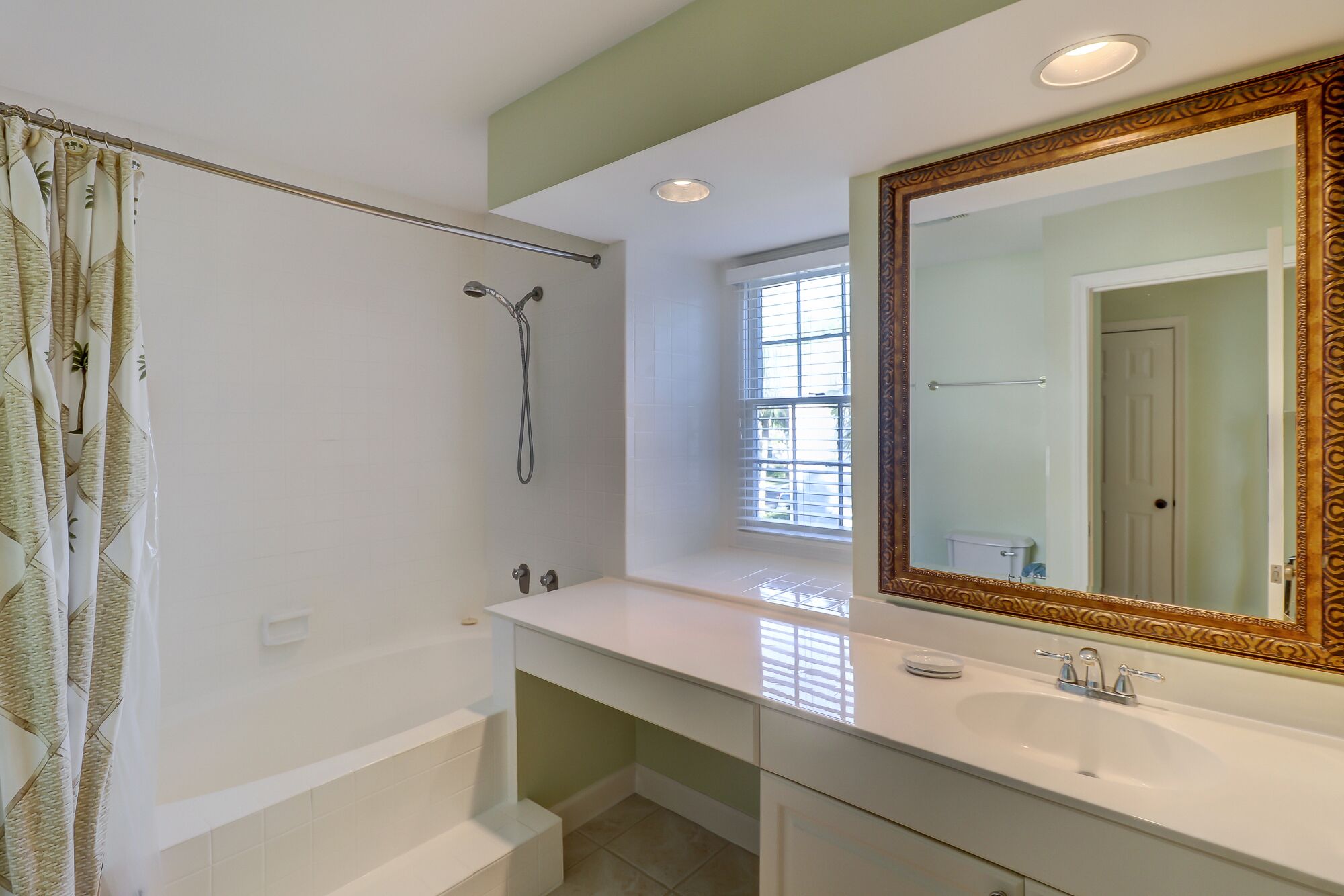 A bathroom with a bathtub, a shower, a large mirror, and a window.