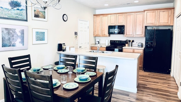 A modern kitchen with wooden cabinets, a black refrigerator, and a dining area with a wooden table and chairs. - Fortune's Edge Retreat by Mesquite Vacation Rentals: Ground Level with 2 Car Garage and $510 in free daily activities (Mesquite)