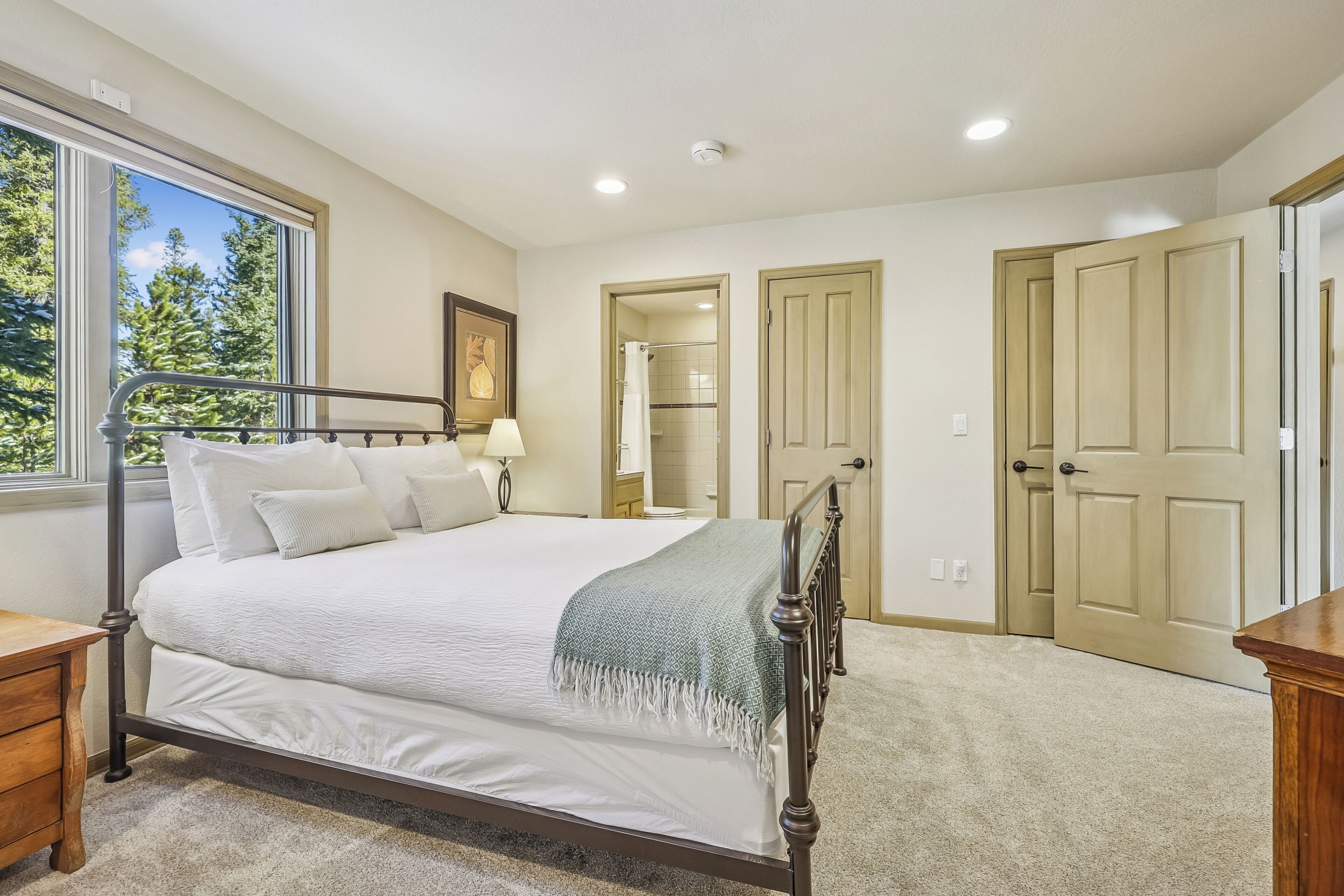 A bedroom with a bed, a nightstand, a window, and a door.