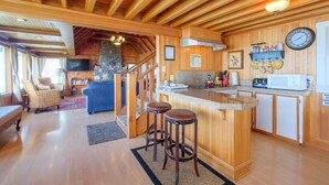 A cozy cabin interior with a wooden interior, a kitchen area with a bar, and a living room with a fireplace. - Steps to the beach, hot tub, sand toys, families love this house. (Lincoln City)