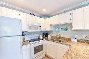 A kitchen with white cabinets, a microwave, stove, and granite countertops.