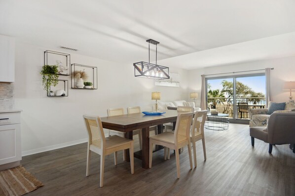 A modern living room with a dining area, large windows, and a balcony.