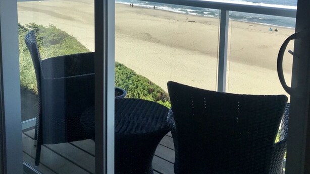 Ein Balkon mit Korbmöbeln mit Blick auf einen Strand und den Ozean.