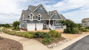 A two-story house with a grey exterior, a front porch, and a driveway. - Doc's Landing: Private Pool, Hot Tub, Currituck Club (Corolla)