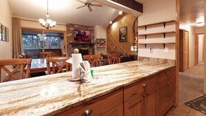 A kitchen with a granite countertop, wooden cabinets, and a ceiling fan. - Motherlode Condo: Walk to Downtown, Slopes (Breckenridge)