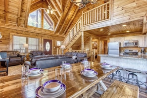 Interior de una cabaña de madera con comedor, cocina y sala de estar.