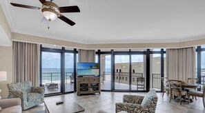 A hotel room with a balcony, a television, and a view of the ocean.